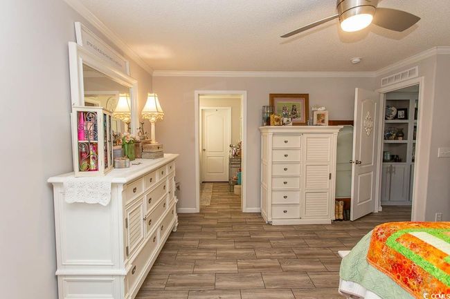 Bedroom featuring visible vents, wood finish floors, ornamental molding, and a ceiling fan | Image 29