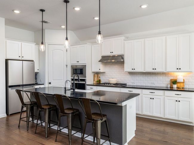 Kitchen featuring under cabinet range hood, dark countertops, visible vents, and stainless steel appliances | Image 5