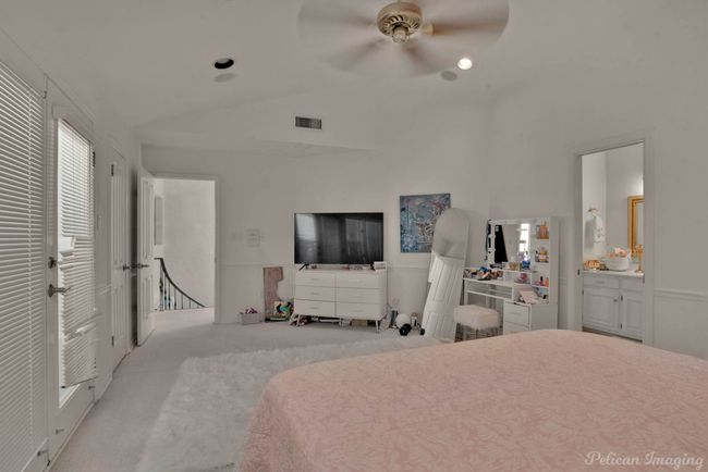 Bedroom with carpet floors, ensuite bathroom, visible vents, ceiling fan, and lofted ceiling | Image 21