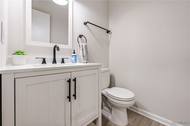 Half bathroom featuring wood finished floors, vanity, toilet, and baseboards | Image 10