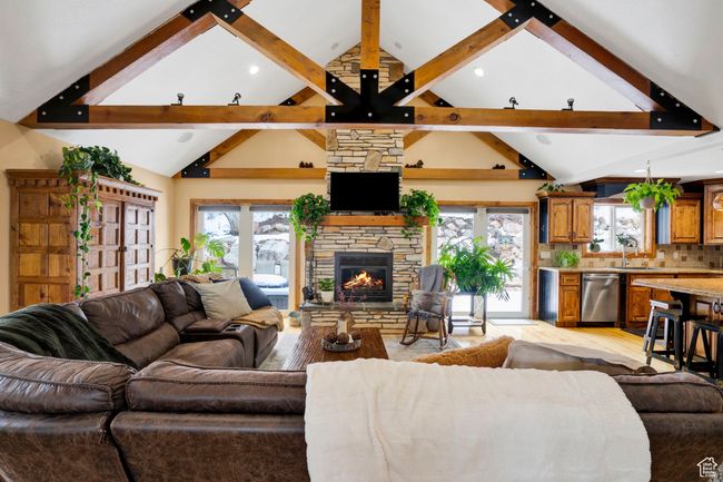 Living area with a stone fireplace, a wealth of natural light, light wood-style flooring, and beam ceiling | Image 8