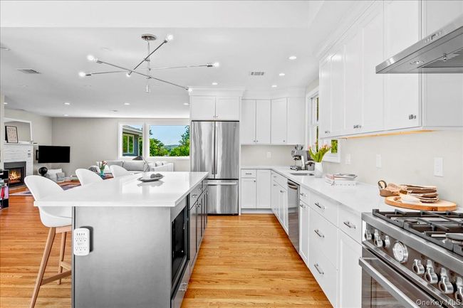 Kitchen with stainless steel appliances, under cabinet range hood, light wood-floors , recessed lighting, and white cabinets | Image 15