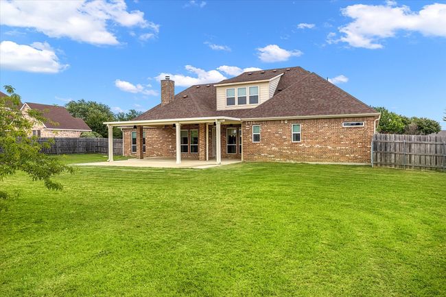 Back of house featuring brick siding, a patio area, a chimney, and a shingled roof | Image 35