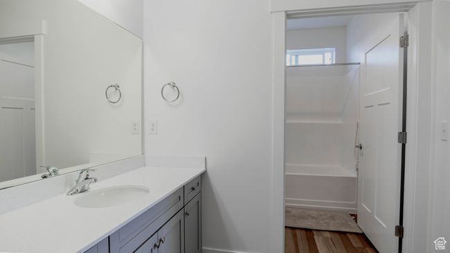 Full bath featuring baseboards, wood finished floors, vanity, and shower combination | Image 24