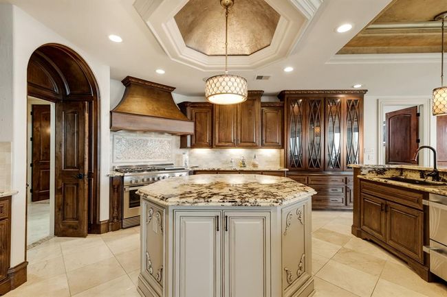 large center island in kitchen with a light that shines through the quartz veins of countertop | Image 17