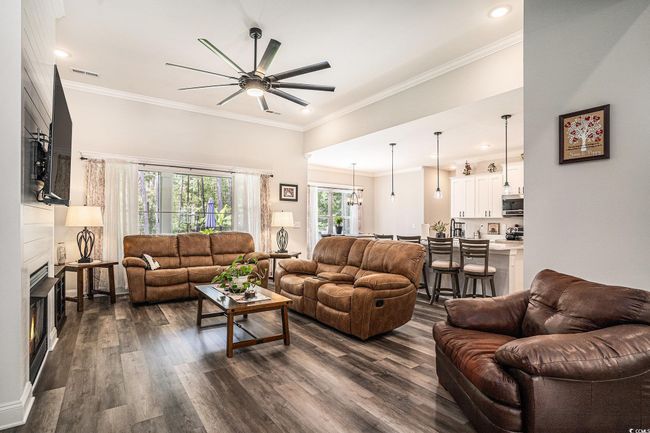 Living room featuring a ceiling fan, dark wood-style floors, a fireplace, crown molding, and recessed lighting | Image 14