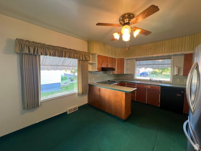 Kitchen with a peninsula, black and stainless steel appliances, under cabinet range hood that is vented to the outside, new dishwasher, wall oven, mail box slot and more. | Image 13