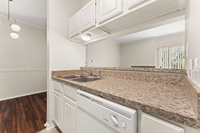 Kitchen featuring a sink, dishwasher, ornamental molding, white cabinets, and dark wood-style flooring | Image 13
