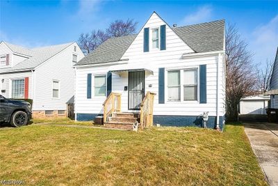 Cape cod home featuring a garage, a front lawn, an outdoor structure, and central air condition unit | Image 2