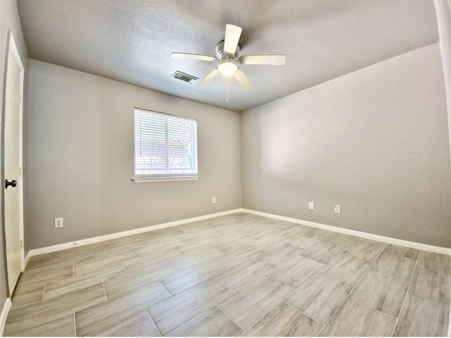 Empty room with ceiling fan, wood tiled floors, and a textured ceiling | Image 22