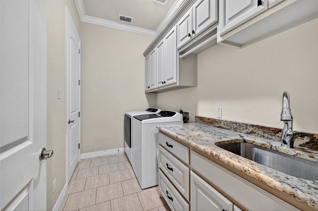 Washroom featuring independent washer and dryer, crown molding, cabinet space, and light tile patterned flooring | Image 18