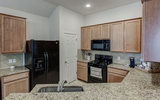 Kitchen with black appliances, a sink, light stone counters, tasteful backsplash, and recessed lighting | Image 5
