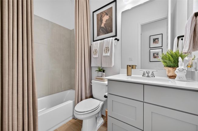 Well-appointed full bathroom featuring a tub/shower combo with tile surround, shaker-style vanity with quartz countertop, and modern fixtures throughout. Neutral tones and clean finishes create a polished and inviting space. | Image 22