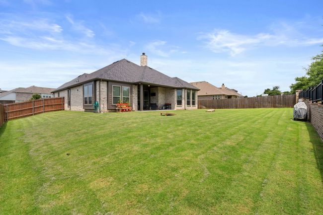 Rear view of property featuring brick siding, a fenced backyard, a chimney, and a shingled roof | Image 38