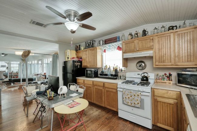Kitchen with white gas stove, under cabinet range hood, ceiling fan | Image 17