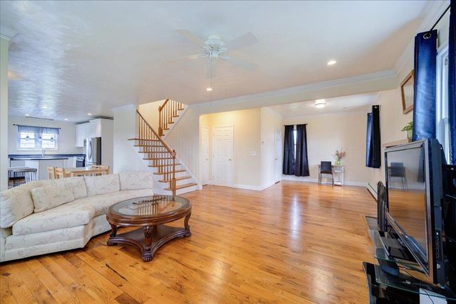 Living area with baseboards, stairway, light wood-style flooring, crown molding, and ceiling fan | Image 11