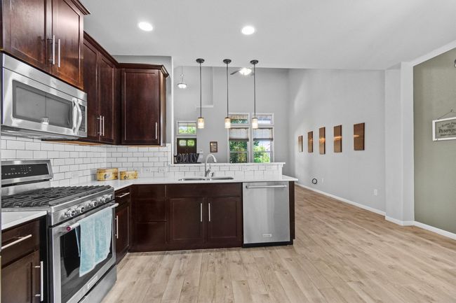 Kitchen featuring stainless steel appliances, a sink, tasteful backsplash, a peninsula, and light countertops | Image 16