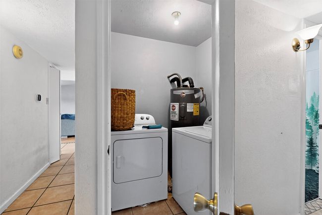 Laundry room featuring washing machine and dryer, water heater, light tile patterned floors, and baseboards | Image 14