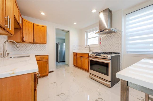 Kitchen with ventilation hood, backsplash, appliances with stainless steel finishes, and a sink | Image 7