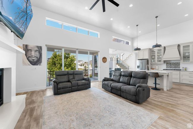 Living room featuring a ceiling fan, stairs, recessed lighting, a high ceiling, and healthy amount of natural light | Image 5