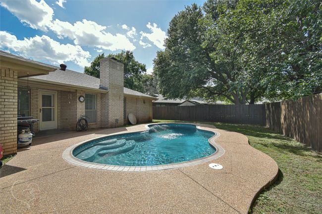 View of swimming pool with a fenced backyard and a patio | Image 5