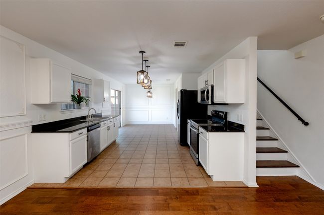 Kitchen featuring visible vents, a sink, stainless steel appliances, white cabinets, and a decorative wall | Image 10