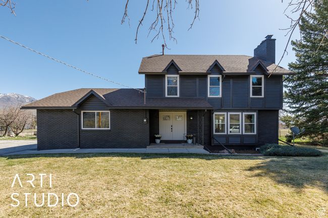 Traditional-style house featuring a front lawn, brick siding, a chimney, and roof with shingles | Image 33