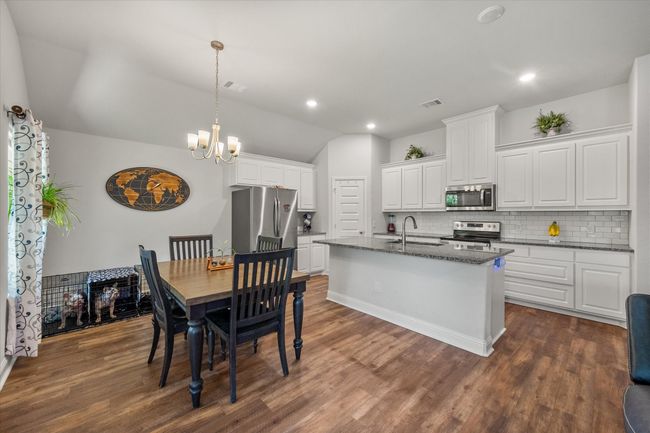 Kitchen with stainless steel appliances, lofted ceiling, backsplash, a chandelier, and white cabinets | Image 13