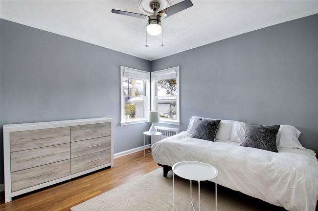Bedroom featuring wood finished floors, baseboards, crown molding, radiator heating unit, and a ceiling fan | Image 7