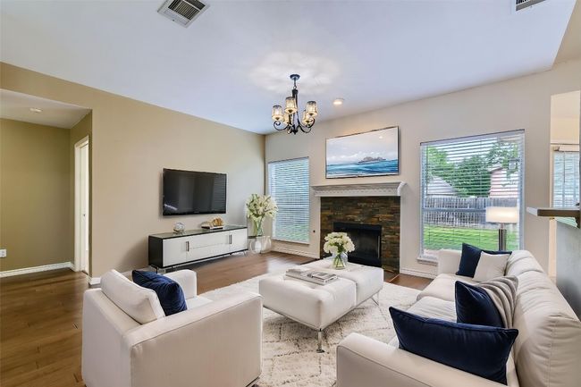 Living room with a chandelier, wood finished floors, a fireplace, and recessed lighting | Image 6