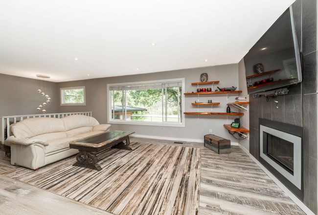 Living area with wood finished floors, a fireplace, baseboards, and recessed lighting | Image 7