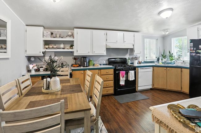 Kitchen featuring black appliances, under cabinet range hood, dark wood-type flooring, a textured ceiling, and light countertops | Image 6