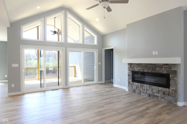 unfurnished living room with wood finished floors, high vaulted ceiling, a fireplace, and a ceiling fan | Image 7