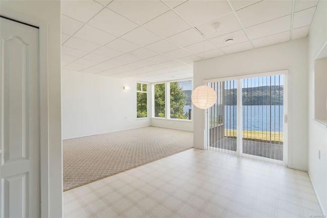 Unfurnished room with a paneled ceiling, tile patterned floors, plenty of natural light, and a water view | Image 43