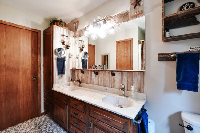 Primary main level bathroom has double sinks and extra storage(1 storage closet and 1 linen cabinet). Over head heat lamp with, bathroom fan, updated lilghting and tiled floors. | Image 14