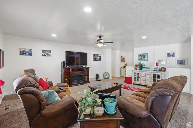 Living area with a textured ceiling, ceiling fan, recessed lighting, and carpet floors | Image 12