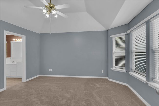 Unfurnished bedroom with carpet, vaulted ceiling, ensuite bathroom, and a ceiling fan | Image 20