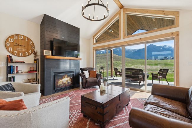 Living area with high vaulted ceiling, an inviting chandelier, a fireplace, and wood finished floors | Image 28