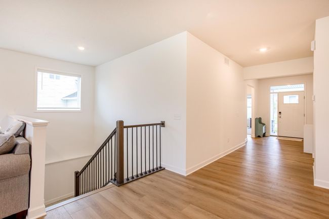 Welcoming foyer with beautiful wood-style flooring and a sleek, modern staircase leading to the lower level. | Image 15