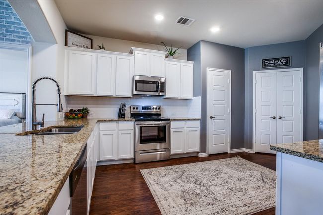 Kitchen with sink, appliances with stainless steel finishes, white cabinetry, and dark hardwood / wood-style floors | Image 10