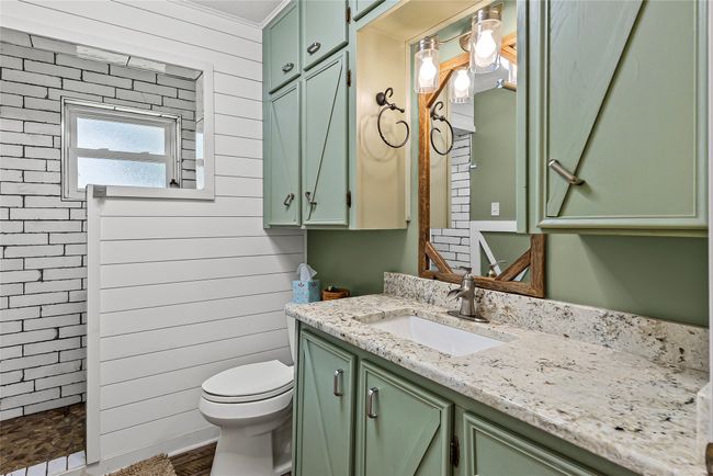 Full bath featuring vanity, tiled shower, and wood walls | Image 16
