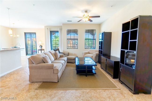Living area with visible vents, baseboards, light tile patterned flooring, and ceiling fan with notable chandelier | Image 6
