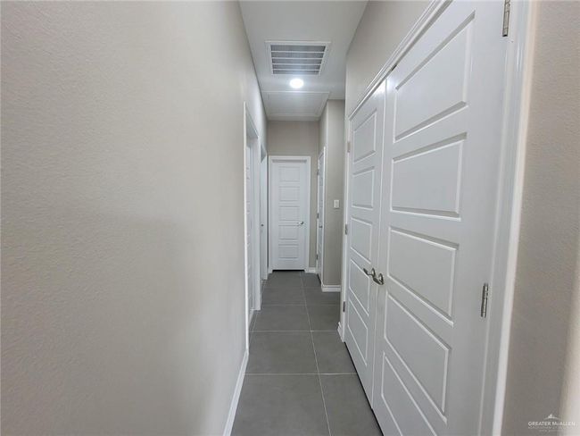 Hallway with dark tile patterned flooring, baseboards, and attic access | Image 14