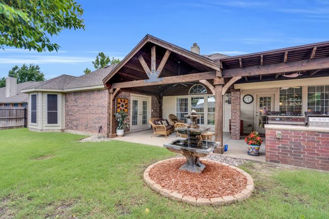 Rear view of property featuring french doors, brick siding, a patio area, a chimney, and a shingled roof | Image 4