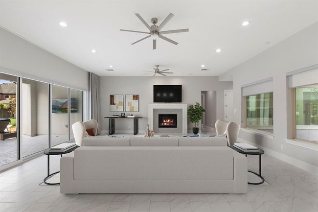 Crisp and contemporary, this sun-drenched living room showcases a sleek fireplace centerpiece, dual ceiling fans, and expansive glass sliders that open to a private backyard oasis—perfectly blending comfort with modern style. *This photo has been virtually staged.* | Image 14