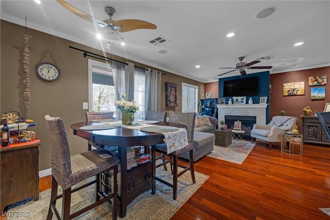 Dining room featuring crown molding, a ceiling fan, wood finished floors, visible vents, and a healthy amount of sunlight | Image 4