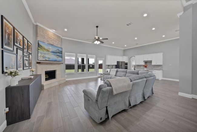 Living area with a stone fireplace, baseboards, ceiling fan, recessed lighting, and ornamental molding | Image 10