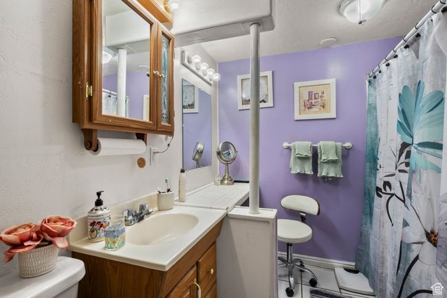 Full bathroom featuring toilet, vanity, tile patterned floors, and curtained shower | Image 24