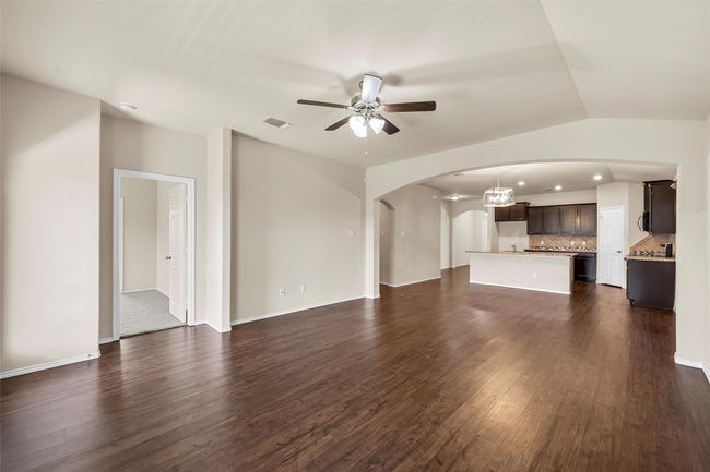 Unfurnished living room with arched walkways, ceiling fan, and dark wood-style floors | Image 17