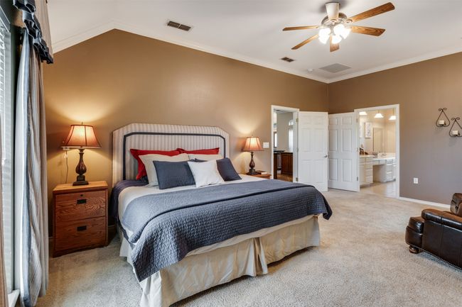 Carpeted bedroom with lofted ceiling, visible vents, and ensuite bathroom | Image 10